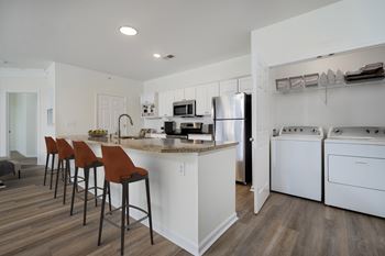 A kitchen with white appliances and brown bar stools.